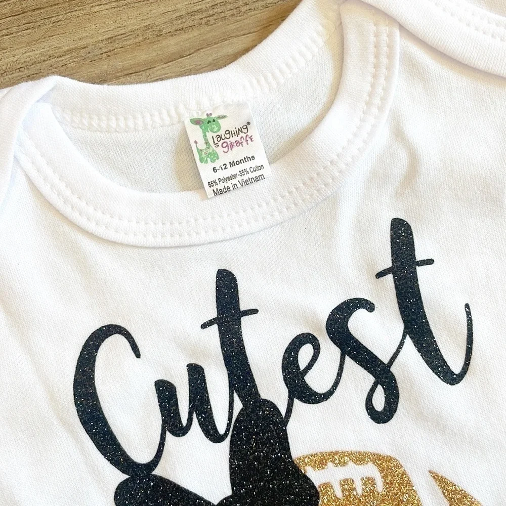Laughing Giraffe Cutest Saints Fan black/gold glitter baby bodysuit
